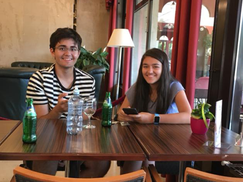 Two kids sitting down and smiling.